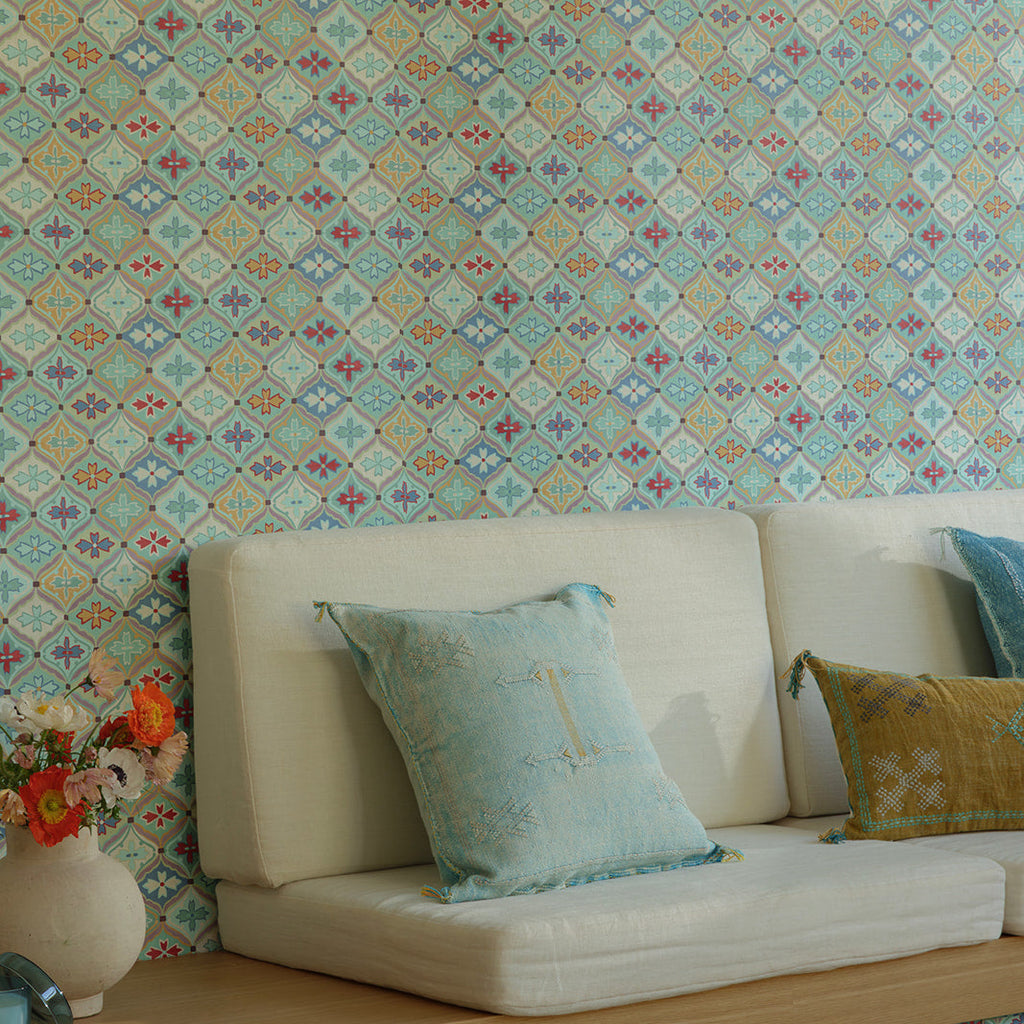 Decorative pillows on a white sofa against a patterned wallpapered wall.