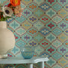 Decorative wall with colorful geometric pattern, white table with vase and bowl, and flowers.