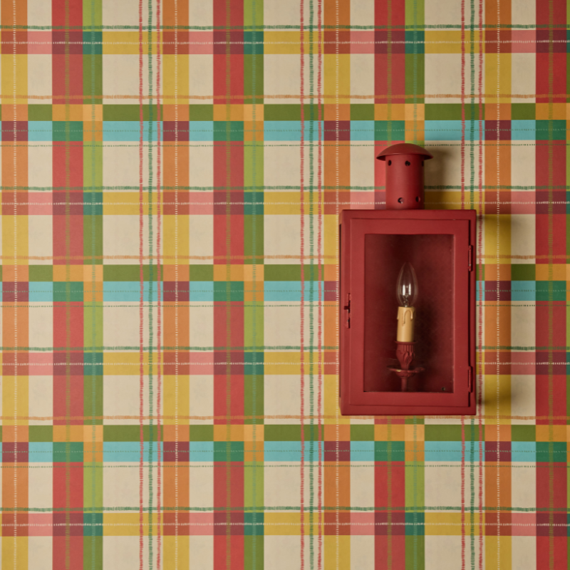 Red wall-mounted lantern with a light bulb inside on a plaid wallpaper background