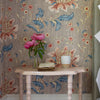 Decorative room with floral wallpaper, pink painted wooden table, and flowers in a vase.