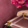 Clear glass tray with gold accents on a maroon surface with pink flowers.