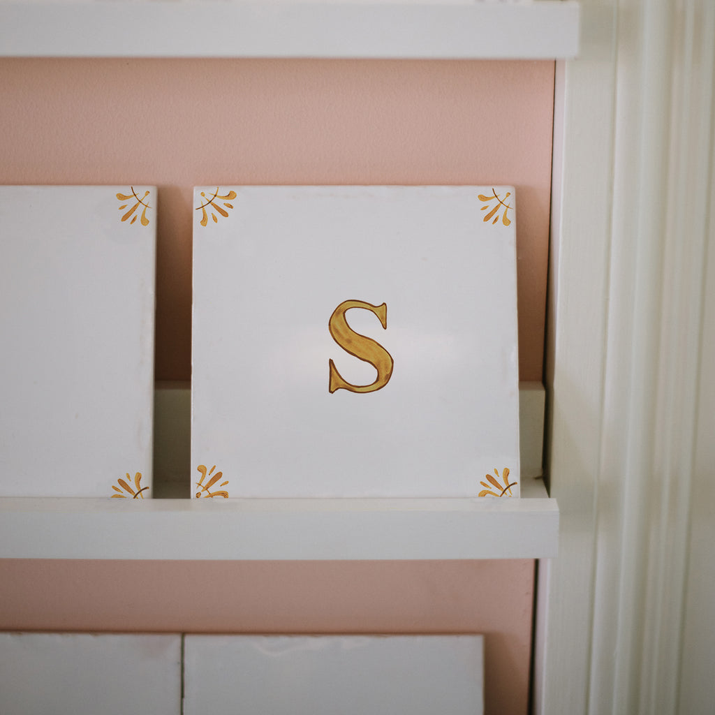 white tiles with mustard delft design and the letter s