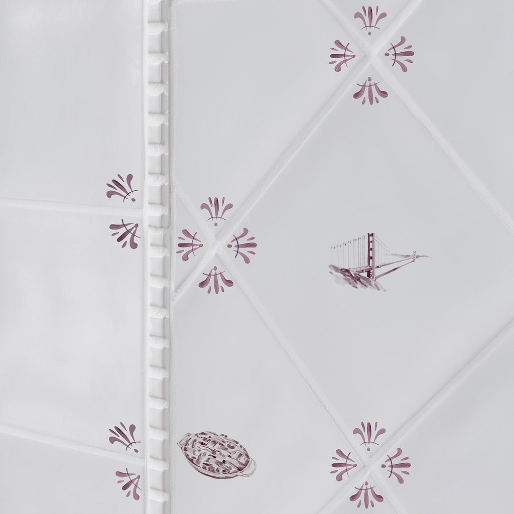 Decorative white tiles with manganese floral patterns and illustrations of the golden gate bridge and an apple pie