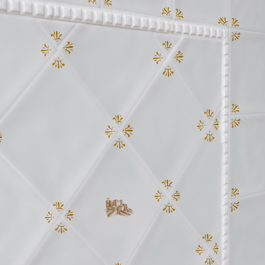 White tiles with mustard floral patterns and a castle design tile on a white background