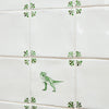 Green dinosaur illustration on a white tile on a tiled wall with decorative corners