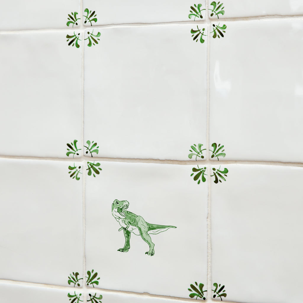 Green dinosaur illustration on a white tile on a tiled wall with decorative corners