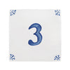 A square white ceramic tile or coaster featuring a large blue painted number 3 in the center, with small blue decorative motifs in each of the four corners.