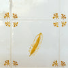 White tile with mustard feather design on a white background