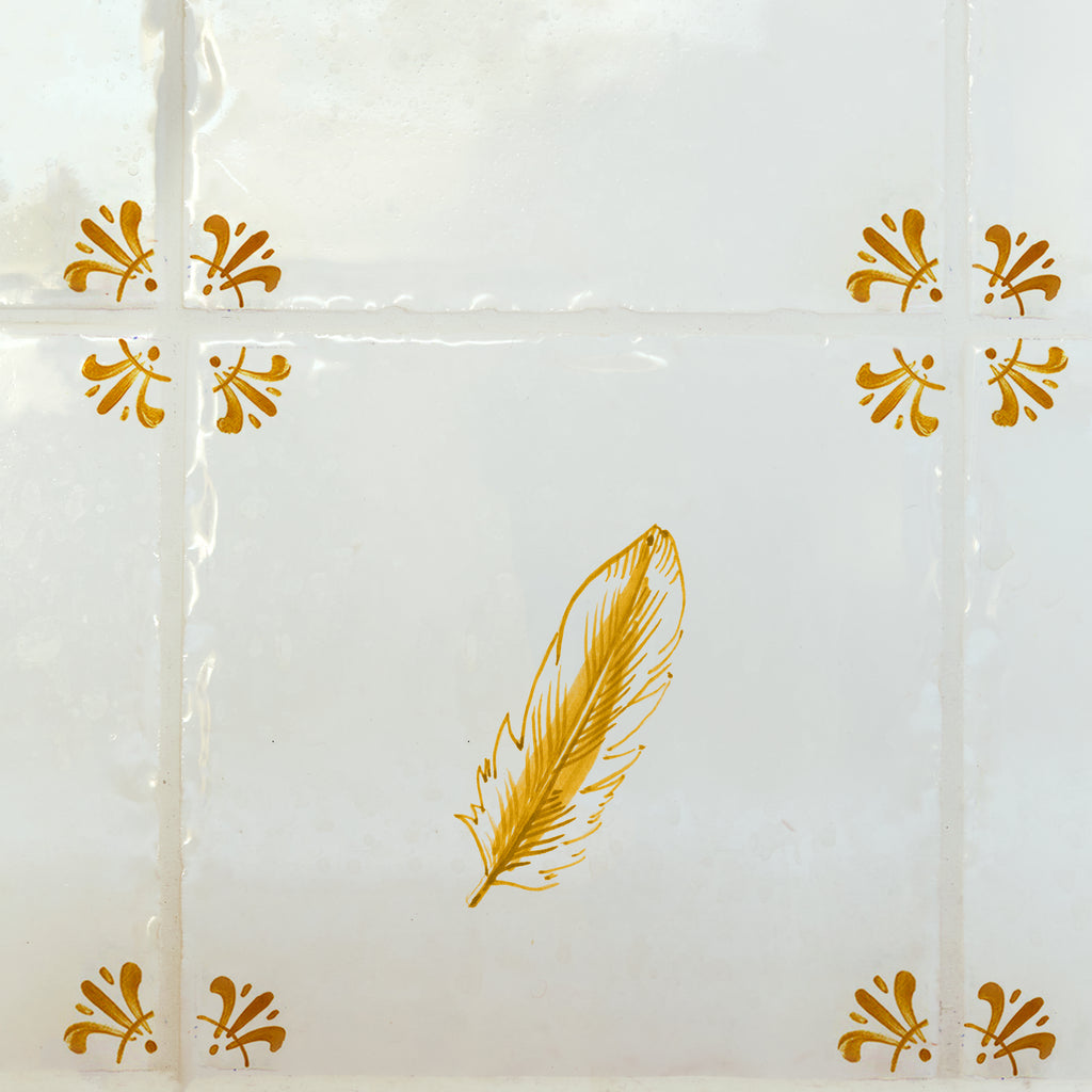 White tile with mustard feather design on a white background