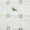 Tiles with Green matcha whisk designs and green decorative corners on a tiled wall