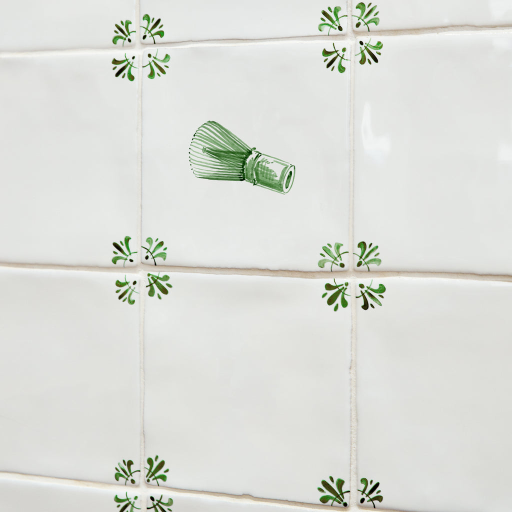 Tiles with Green matcha whisk designs and green decorative corners on a tiled wall