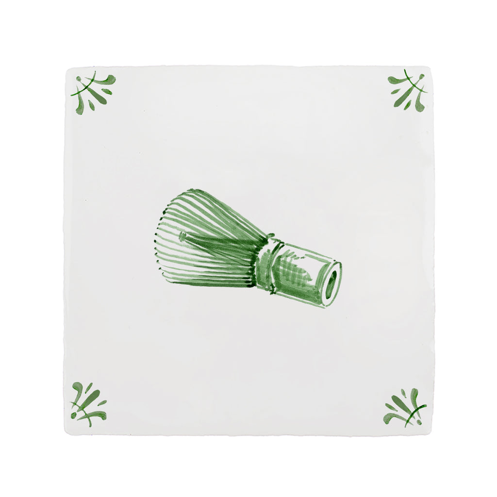 Green tea whisk on a white tile background with green decorative corner patterns