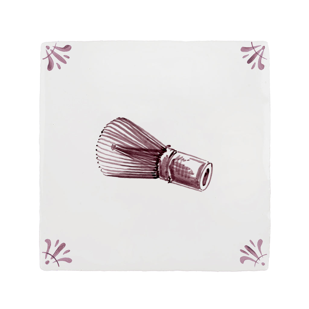 Purple matcha whisk on a white tile background with decorative patterns