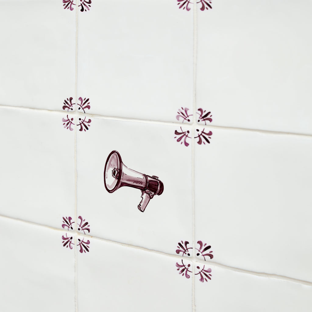 Megaphone tile on a tiled wall with decorative floral patterns