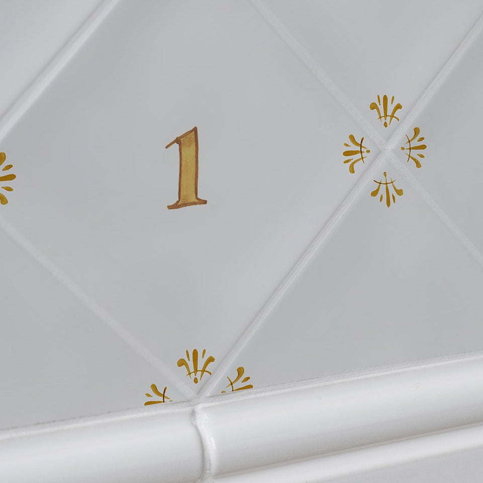 White tiled wall with mustard decorative elements and number '1'.