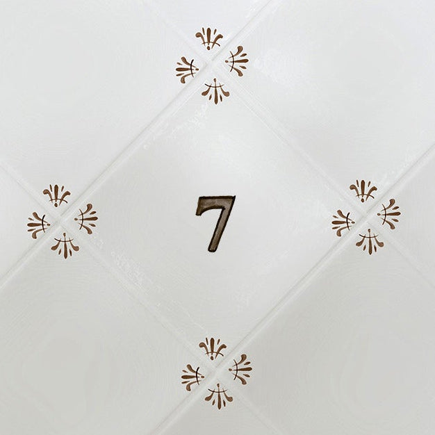 Close-up of a tiled white surface with decorative patterns and a number '7'.