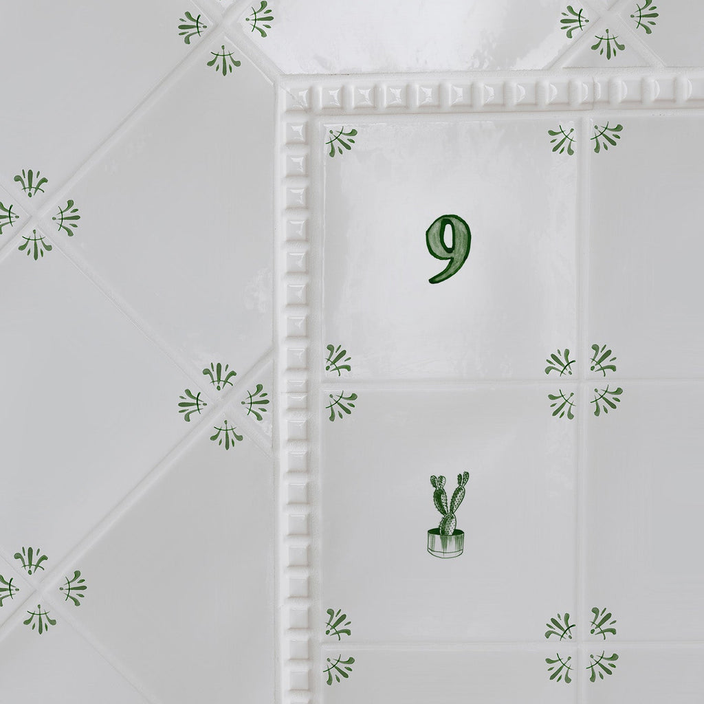 White tiles with green floral patterns and a number '9' on a white background